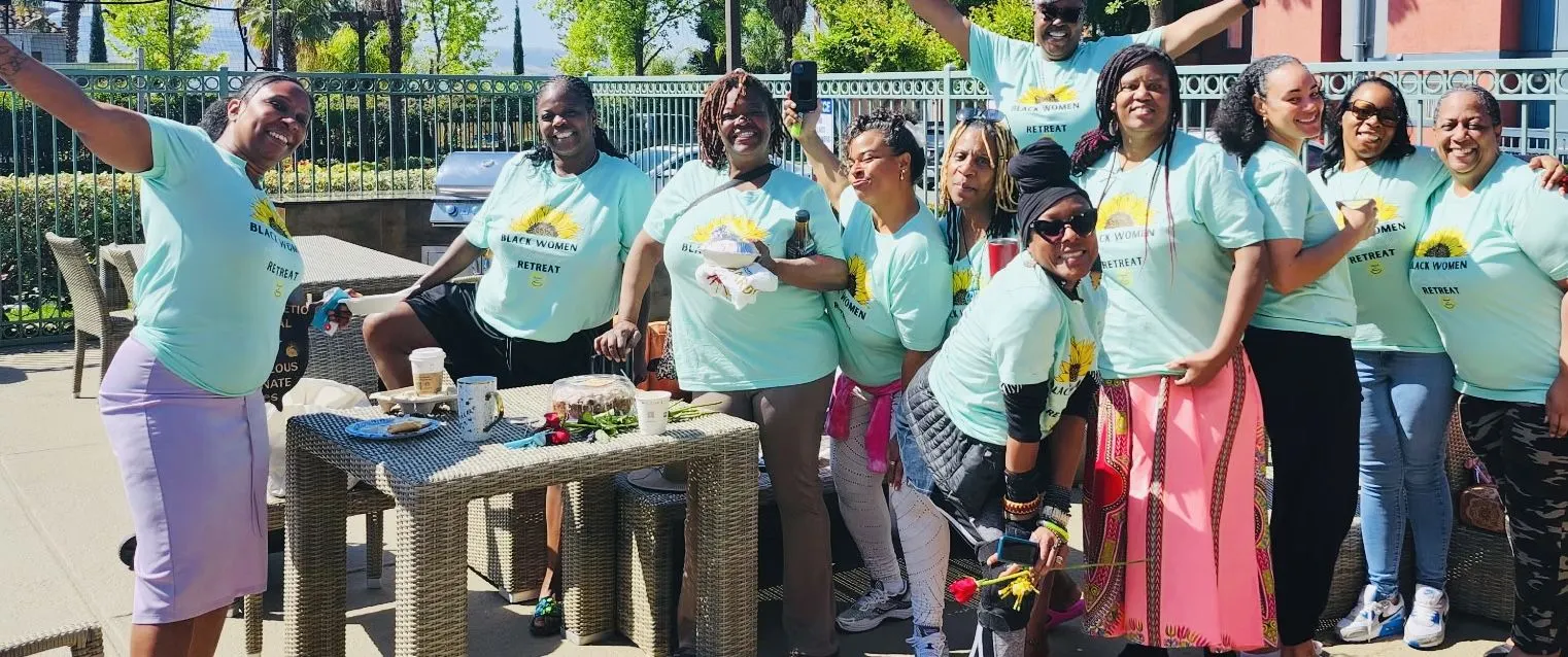 Retreat participants in matching teal shirts celebrating outdoors